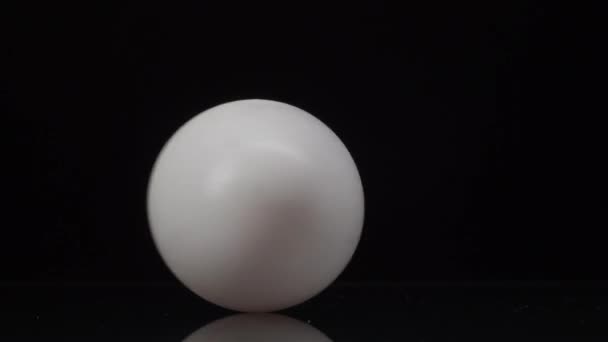 4K video de huevo de gallina blanca girando sobre un fondo negro con reflexión — Vídeos de Stock