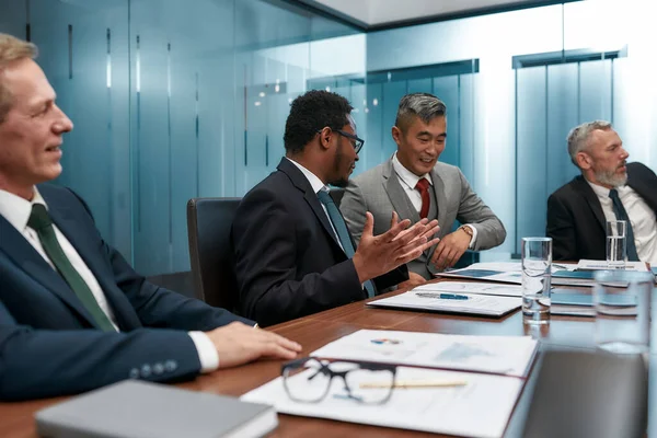 Gente de negocios multicultural en ropa formal discutiendo un nuevo proyecto mientras tienen una reunión en la oficina moderna — Foto de Stock
