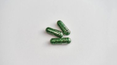 Işıkta yeşil parıltı hapları olan yaratıcı bir kavram, beyaz arka plan. Asgari biçim.