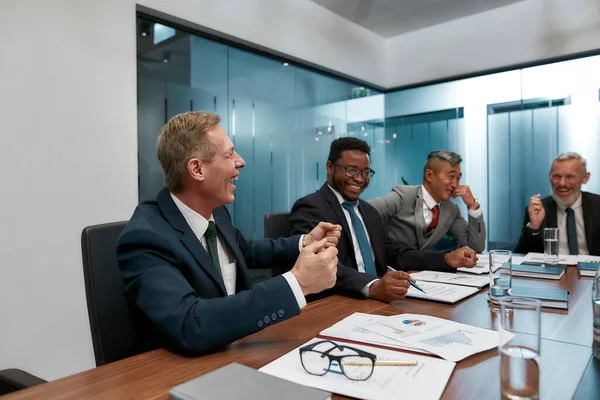 Un equipo fuerte. Gente de negocios multicultural en ropa formal discutiendo algo y sonriendo mientras tienen una reunión en la oficina moderna — Foto de Stock