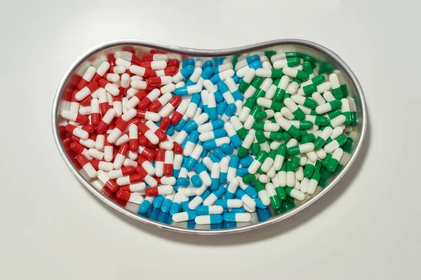 Плоский лежал, вид сверху на разные таблетки, капсулы, лежащие в металлической коробке на белом фоне. Здоровье, витамины и концепция лечения — стоковое фото
