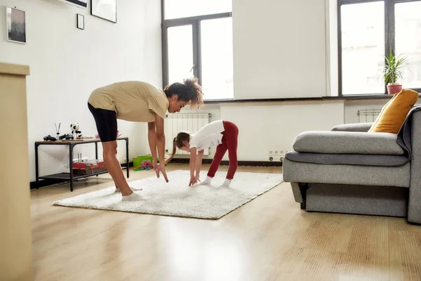 Una mejor manera de practicar la atención. Mujer afroamericana niñera y niña linda caucásica que tiene entrenamiento en casa. Educación infantil, actividades de ocio, concepto de cuidado de niños —  Fotos de Stock