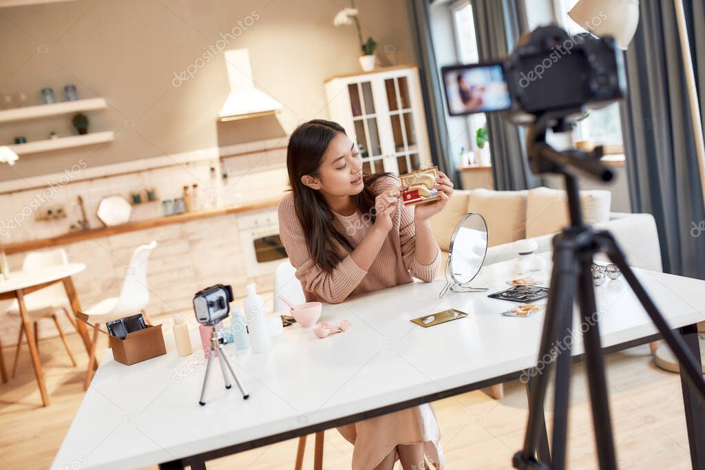 New perspective. Young female blogger recording a tutorial video for her beauty blog about skincare routine. Vlogger showing eye patch, recording video for social network