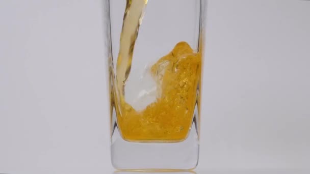 Elisir sano. Super slow motion colpo dettagliato di versare delizioso succo di mela fresco in un bicchiere trasparente su sfondo bianco — Video Stock