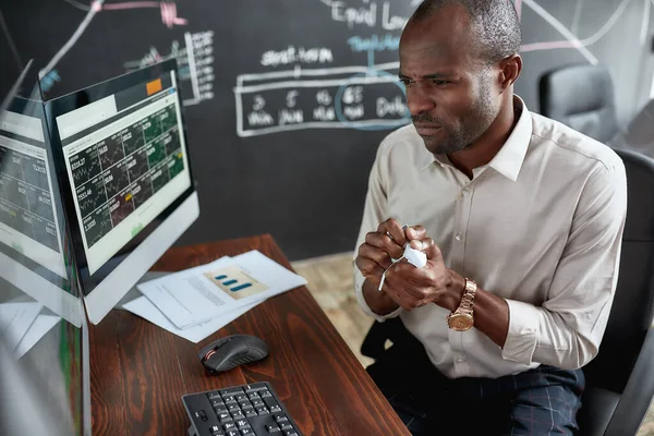 Er is geld nodig. Stijlvolle Afrikaanse zakenman, handelaar aan bureau voor meerdere monitors. Hij wordt boos terwijl hij de papieren verkruimelt.. — Stockfoto