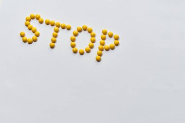 Arka planda sarı haplardan yapılmış bir kelime var. Hastalığı durdur. Sağlık ve tedavi kavramı