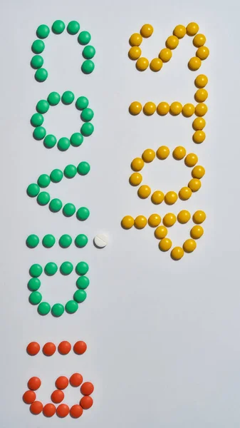 Palavra PARAR COVID 19 feito de comprimidos médicos amarelos, verdes, vermelhos, comprimidos em fundo claro. Conceito de cuidados de saúde e tratamento — Fotografia de Stock