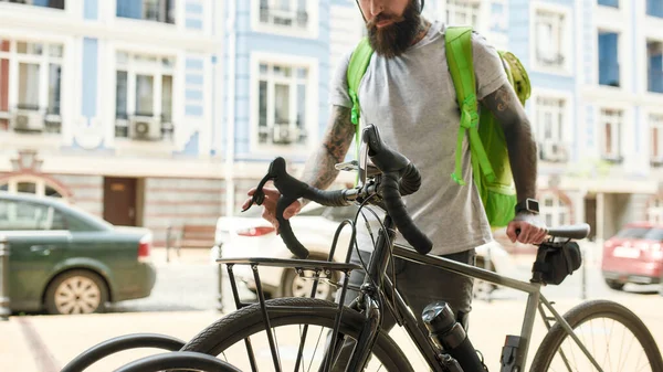 Zrób to odpowiednio. Ujęcie brodatego kuriera z torbą termiczną lub plecakiem parkującym na rowerze, dostarczającym jedzenie. Kurier, koncepcja usługi dostawy — Zdjęcie stockowe