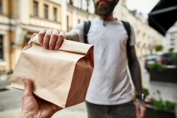 Tiro cortado do homem da entrega que prende o saco de papel ao dar afastado a ordem a um cliente. Correio, conceito de serviço de entrega — Fotografia de Stock