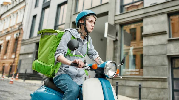 Junge Frau mit Helm und Thermo-Rucksack auf einem Motorroller, Essensausgabe. Kurier, Lieferservice, Lockdown-Konzept — Stockfoto