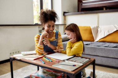 Olması gerektiği gibi çocuk bakımı deneyimi. Kafkasyalı küçük kız Afrikalı Amerikalı bebek bakıcısıyla vakit geçiriyor. Çizim yapıyorlar, çizim yapmayı öğreniyorlar, yerde oturuyorlar.
