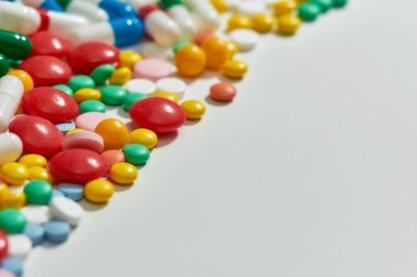Farklı hapları kapatın, kapsüller çapraz olarak beyaz arka plana saçılmış. Sağlık, vitamin ve tedavi kavramı