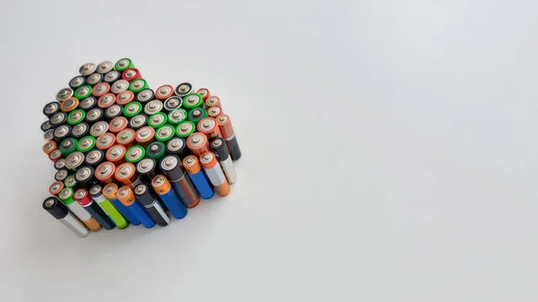 Many alkaline batteries in the shape of a heart on white background. Concept of recycling waste and environmental pollution — Stock Photo, Image