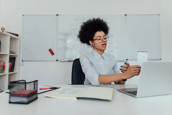 École d'anglais en ligne. Jeune enseignante afro-américaine expliquant les règles de la grammaire anglaise tout en donnant des cours en ligne par webcam à la maison — Photo