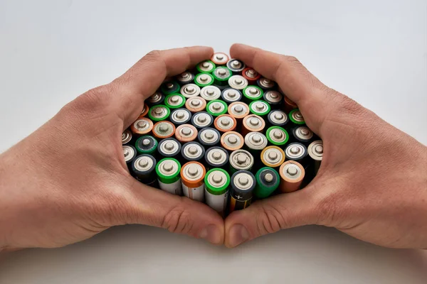 Think outside the trash, recycle. Close up of hands holding many alkaline batteries on white background. Concept of recycling waste and environmental pollution — Stock Photo, Image