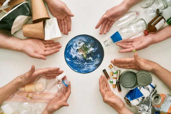 Ta vie, ton monde, notre avenir. flatlay conceptuel avec de nombreuses mains et différents déchets, types d'ordures atteignant la planète Terre en papier au centre sur fond blanc — Photo