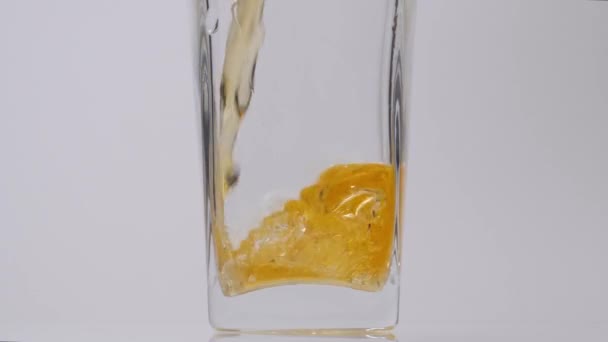 Hemlagad äppeljuice. Slow motion detaljerad bild av hälla läckra färska äppeljuice i ett transparent glas mot vit bakgrund — Stockvideo