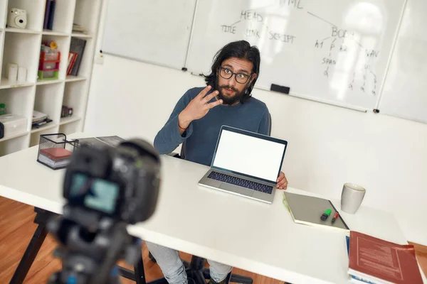 Jeune enseignant assis à son lieu de travail et expliquant nouveau thème tout en enregistrant blog vidéo sur l'équipement numérique professionnel. Classe de codage en ligne — Photo