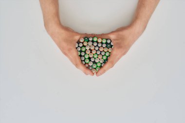 Top view of hands holding many alkaline batteries on white background. Concept of recycling waste and environmental pollution clipart