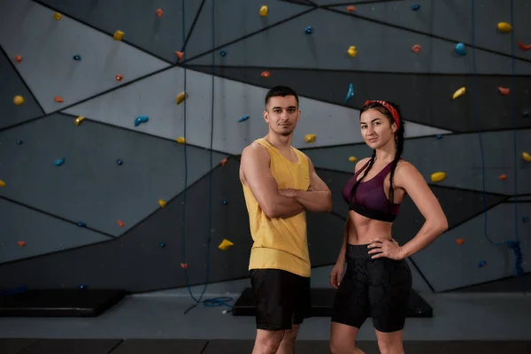 Climbers Rock. Active young man and woman in sportswear looking at camera, standing against climbing wall. Concept of sport life and rock climbing