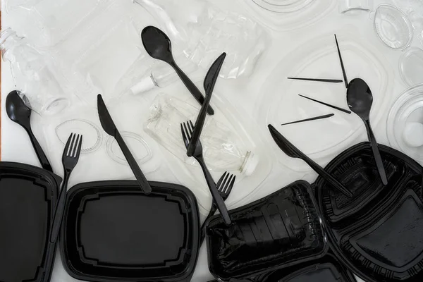 Flatlay composition with used black and white plastic containers over white background