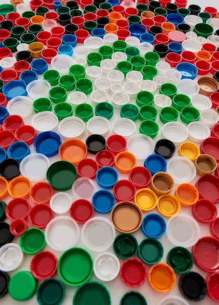 Close up of collage with colorful plastic bottle caps and recycling sign on white background. Reuse of waste concept. — Stock Photo, Image