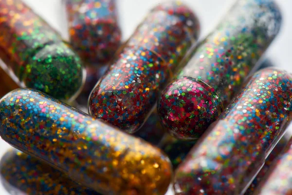 Kreativní koncept s mnoha barevných třpytivých pilulek rozptýlené, ležící náhodně. Minimální styl, umělecký koncept — Stock fotografie