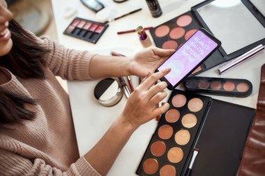 Bu uygulamayı dene. Güzellik blogcusu kadın reklam uygulamasını kapat, akıllı telefon tut. Makyaj uzmanı Asyalı kız evde kozmetik ürünleri incelerken uygulama kullanıyor.