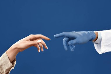 Connection between doctor and patient. Hands of doctor in sterile glove and female patient touching each other with fingers. Isolated on navy blue background clipart