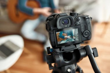 İnternetten gitar çalmayı öğren. Erkek öğretmen evdeki kanepede oturup gitar çalmayı öğretiyor. Webinar 'ı evde kaydediyorum. Uzaktan eğitim. Kameraya odaklan.