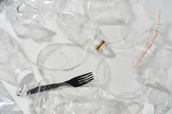 Composición plana con botellas de plástico usadas, recipientes, tenedores, cucharas, envases de huevo, tapas sobre fondo blanco — Foto de Stock