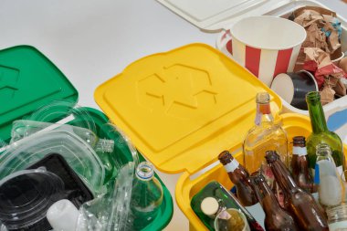 Üç renkli yeşil, sarı ve beyaz çöp tenekeleri beyaz arka planda izole edilmiş. Atık ayırma kavramı