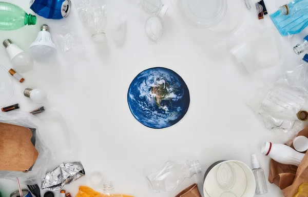 Composition Flatlay avec différents déchets, types de déchets et modèle de papier de la Terre au centre sur fond blanc — Photo