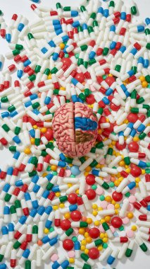 Farklı ilaç ve kapsüllerin üzerinde duran insan beyni modelini kapatın. Sağlık ve tedavi kavramı