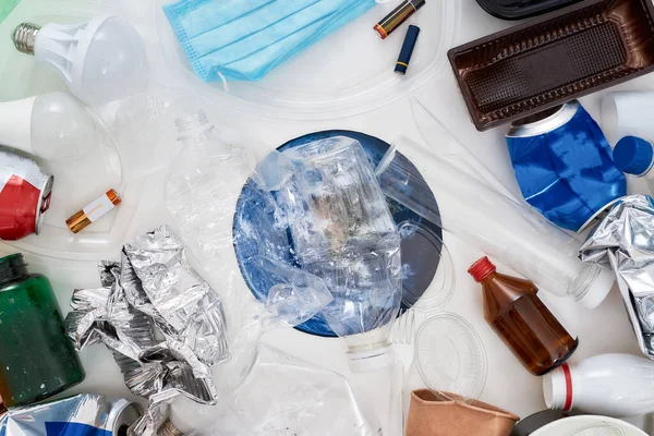 Composición plana con diferentes residuos, tipos de basura y modelo de papel de la Tierra debajo de ella en el centro sobre fondo blanco — Foto de Stock