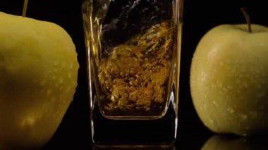 Taze sıkılmış elma suyu. Yavaş çekim. Lezzetli elma suyu bardağa, yeşil elma suyu da siyah arka plana dökülür.
