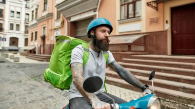 Özel bir güzergahta. Kasklı, termal çantalı ya da sırt çantalı bir teslimatçı şehirde motosikletle yiyecek getiriyor. Kurye, teslimat hizmeti konsepti