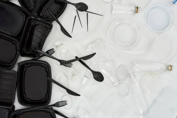 Flatlay composition with empty black and white plastic containers over white background