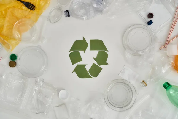 Aproveite a natureza. Reciclar. Composição plana com diferentes garrafas de plástico vazias, recipientes e placa de reciclagem feita de papel no centro sobre fundo branco — Fotografia de Stock