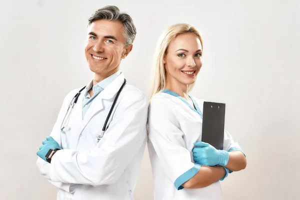 Squadra medica di successo. Due medici allegri, uomo e donna in uniforme medica con le braccia incrociate, guardando la macchina fotografica e sorridendo — Foto Stock