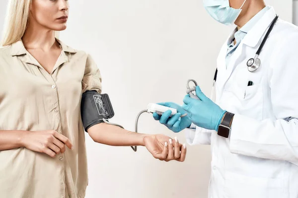 若い女性の血圧を測定医療制服、保護顔マスクと青滅菌手袋の男性医師、女性患者 — ストック写真