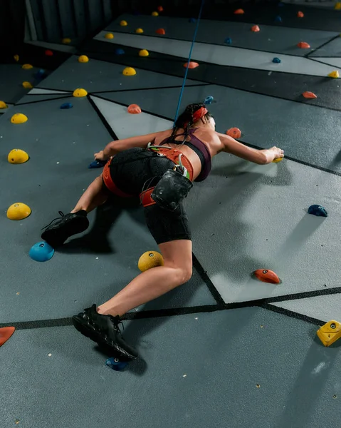 Mujer en equipo de seguridad y entrenamiento de arnés en la pared de escalada artificial en interiores —  Fotos de Stock