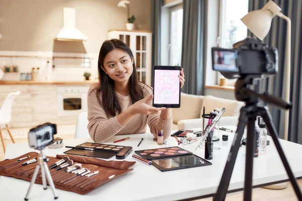 Ό, τι χρειάζεσαι. Beauty blogger γυναίκα μαγνητοσκόπηση, διαφήμιση app στην κάμερα, κρατώντας tablet PC. Makeup influencer ασιατική κορίτσι καταγραφή καλλυντικά αναθεώρηση του προϊόντος στο σπίτι — Φωτογραφία Αρχείου