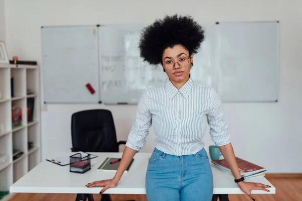 Portré fiatal professzionális afro amerikai nő alkalmi ruhákban nézi a kamerát, miközben tanít idegen nyelv online otthonról. Fehértábla a háttérben — Stock Fotó