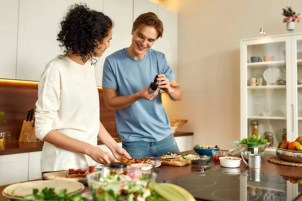 我们就是这样做的。一对快乐的夫妇在厨房的摄像头上记录素食健康食品的视频博客。年轻男女在做早餐。素食，饮食，待在家里的观念 — 图库照片
