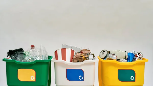 Conjunto de tres coloridos contenedores de basura de reciclaje verde, amarillo y blanco con letrero de reciclaje lleno de basura aislada sobre fondo blanco. Concepto de separación de residuos — Foto de Stock