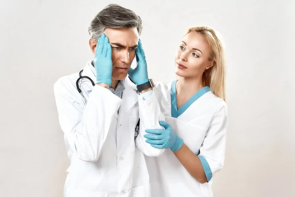 Dühös férfi orvos fogdossa a fejét, miközben a női kollégája vigasztalja, az orvosi csapat együtt dolgozik egy kórházban. — Stock Fotó