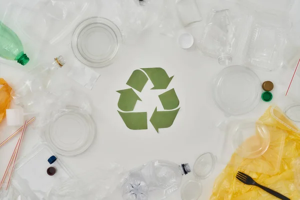 Todo sobre reciclaje. Composición plana con diferentes botellas de plástico vacías, contenedores y signo de reciclaje de papel en el centro sobre fondo blanco —  Fotos de Stock