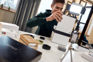 Hadi birlikte açalım. Genç erkek teknoloji blogcusu video blogu veya video blogu kaydediyor. Yeni kamera lensleri ve diğer cihazlar hakkında. Bloglama, Evden Çalışma kavramı