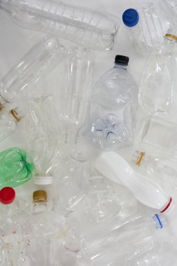 Beyaz zemin üzerinde farklı boş plastik şişeler içeren düz konum